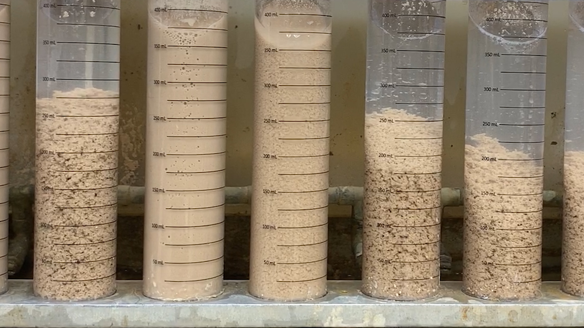 Multiple test tubes with wastewater showing how the sediment reacts to polymer flocculants and settles to the bottom of the tubes.