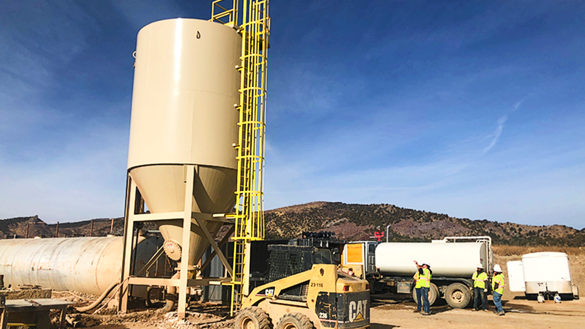 A vertical thickener being installed at a sand site with men standing around.