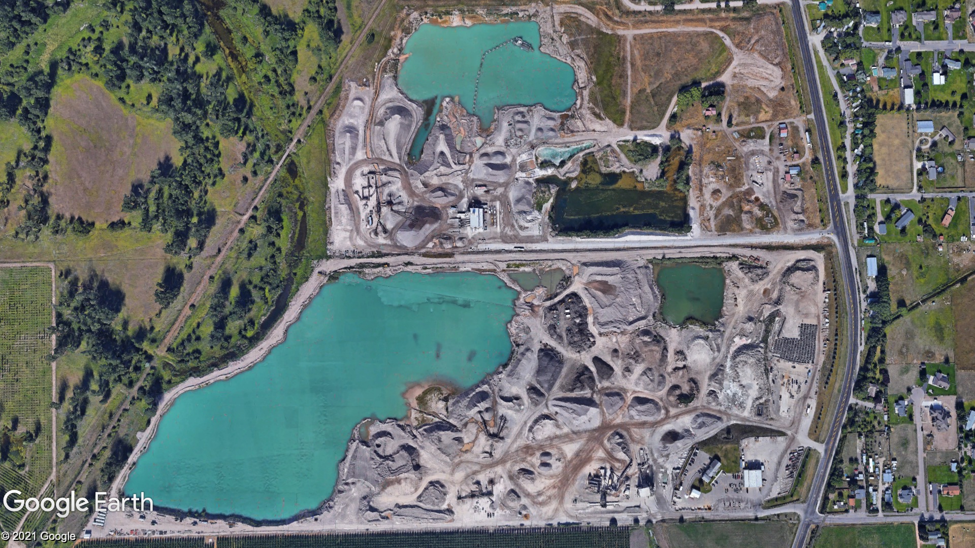 A satellite image showing an aggregate production site with large ponds and rock piles.