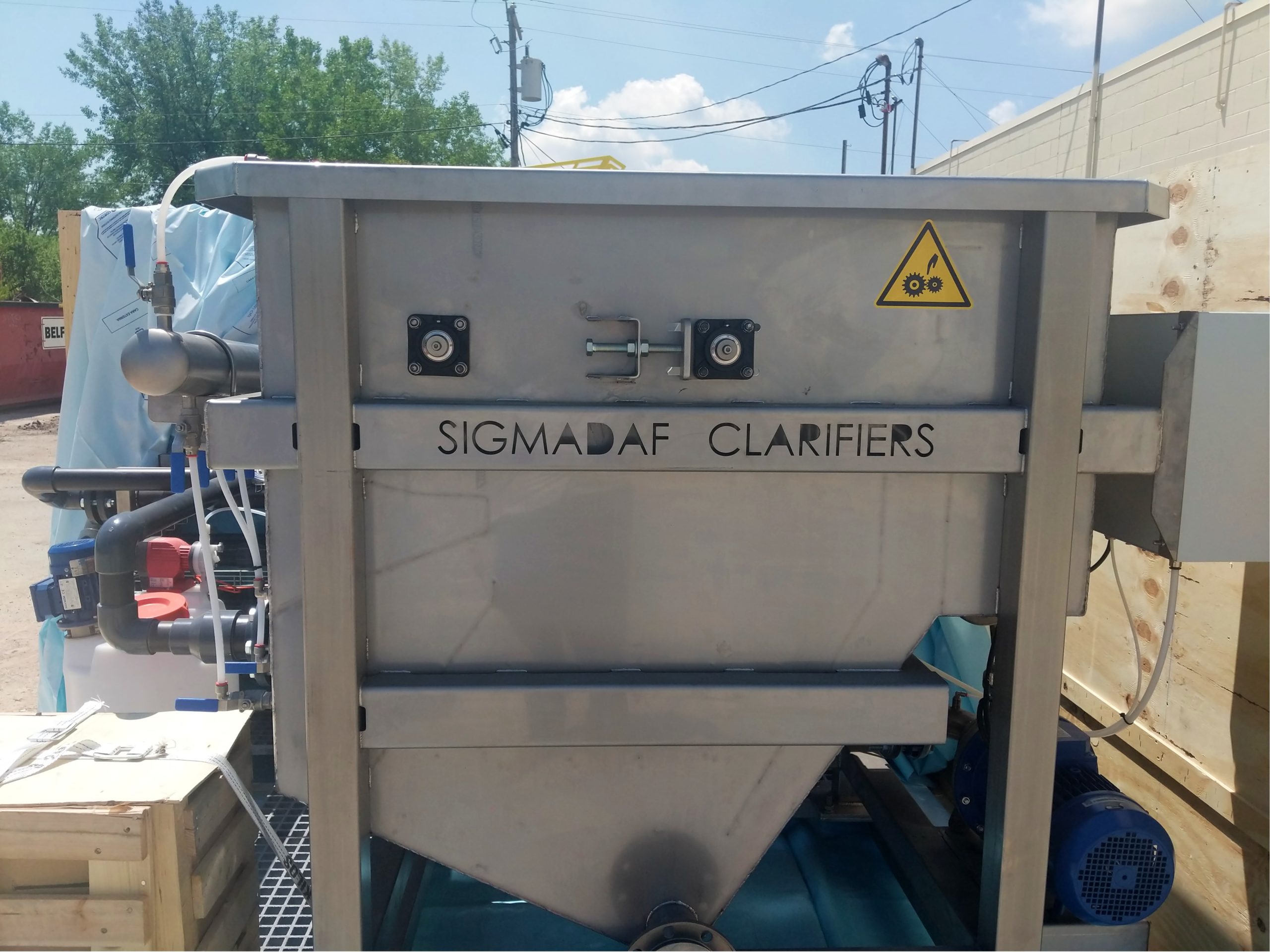 A large stainless steel tank pictured outside with SigmaDAF Clarifiers stamped into it.