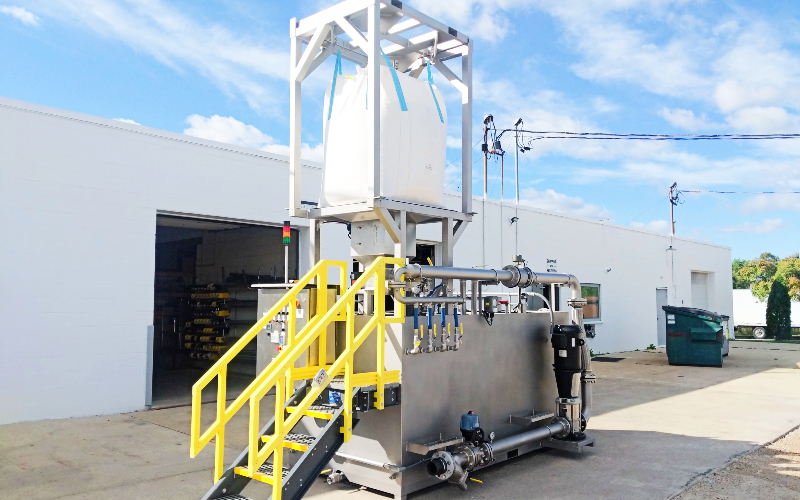 A large stainless steel dry polymer system with a big bag of polymer.