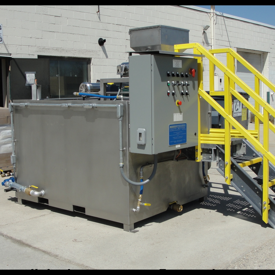 A dry stainless steel chemical preparation system outside with a switch control panel and yellow handrails on the stairs.